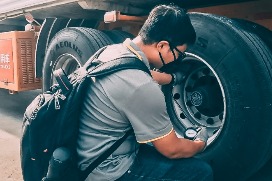 Man observing tire with chinstrap and gloves
